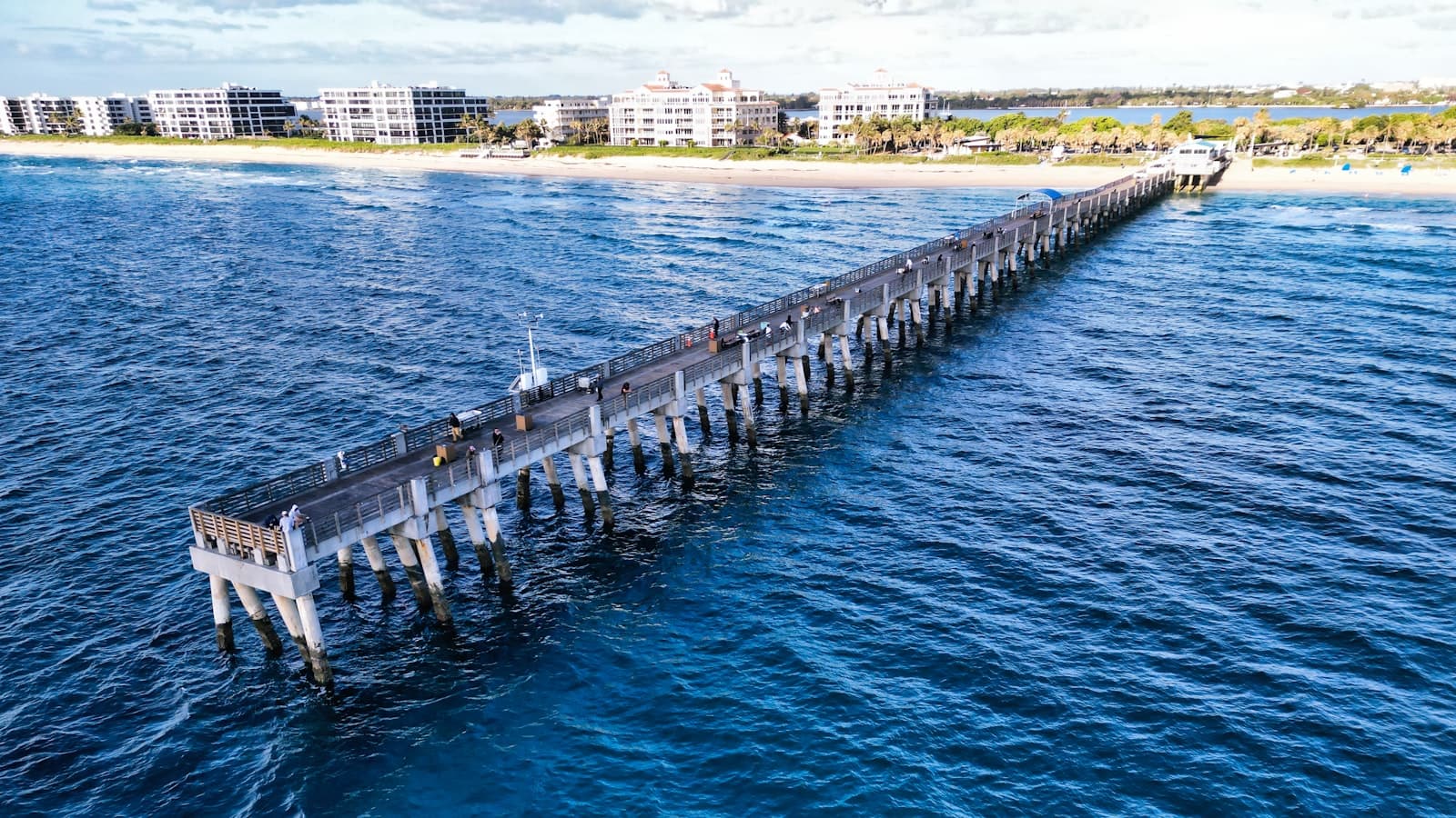 Atlantic waves beside a long fishing pier and pale coastal buildings.